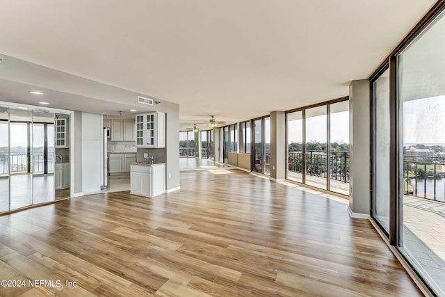 unfurnished living room with light hardwood / wood-style flooring, a healthy amount of sunlight, and a wall of windows