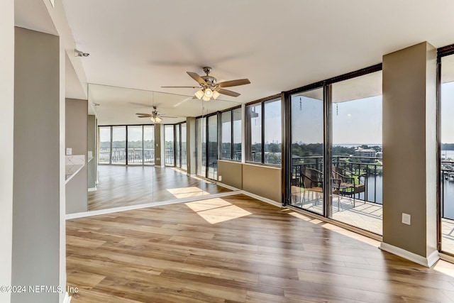 unfurnished sunroom featuring ceiling fan and a water view