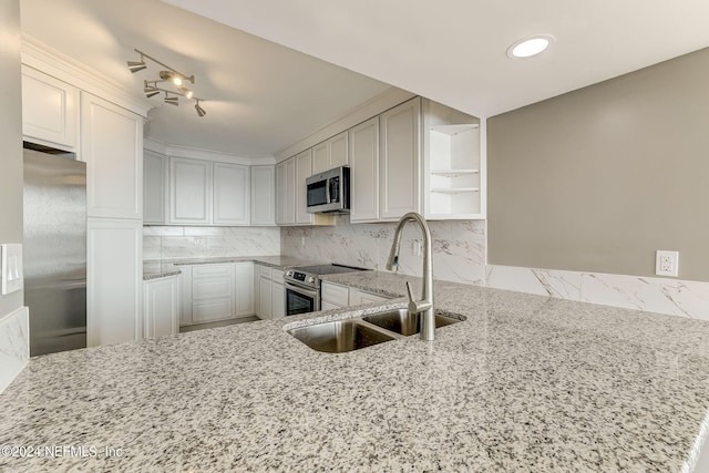 kitchen with sink, white cabinets, light stone counters, and stainless steel appliances