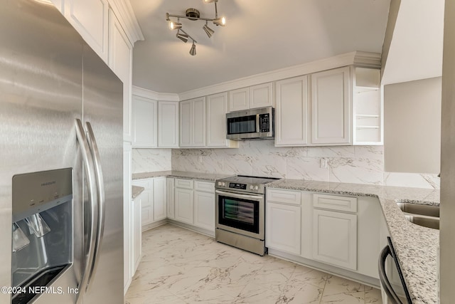 kitchen with white cabinetry, sink, stainless steel appliances, tasteful backsplash, and light stone counters