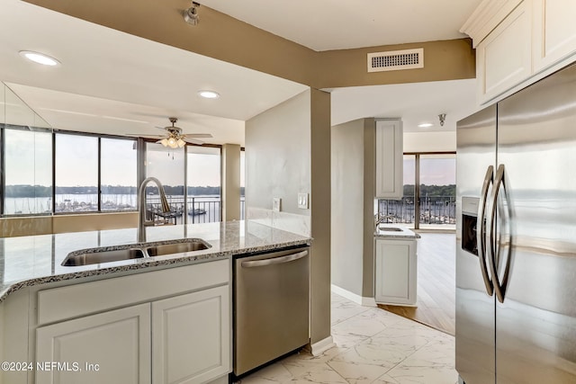 kitchen featuring appliances with stainless steel finishes, light stone counters, ceiling fan, sink, and white cabinetry