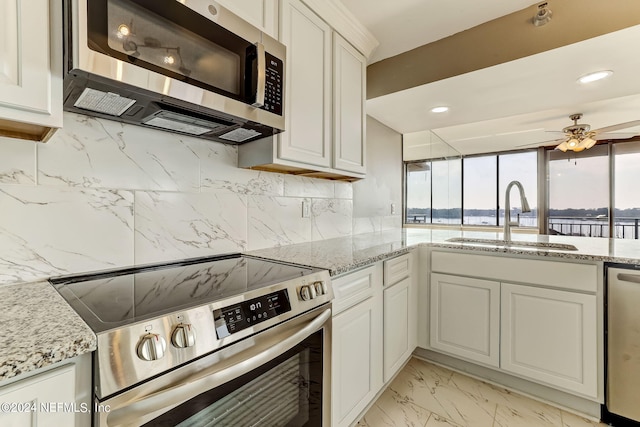 kitchen with sink, decorative backsplash, light stone counters, white cabinetry, and stainless steel appliances