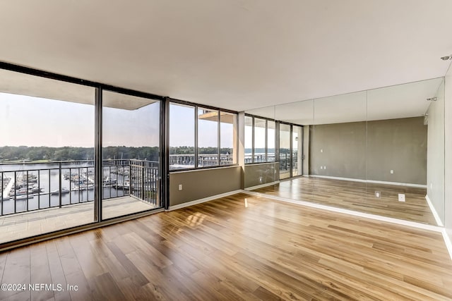 spare room with a water view and wood-type flooring