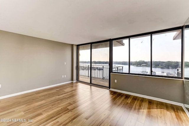 unfurnished room with hardwood / wood-style floors and a water view