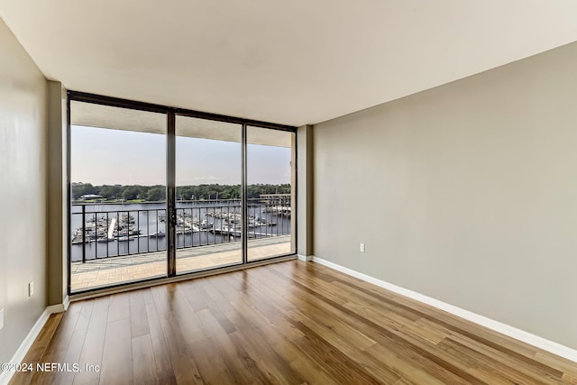 spare room featuring a water view, expansive windows, and hardwood / wood-style flooring