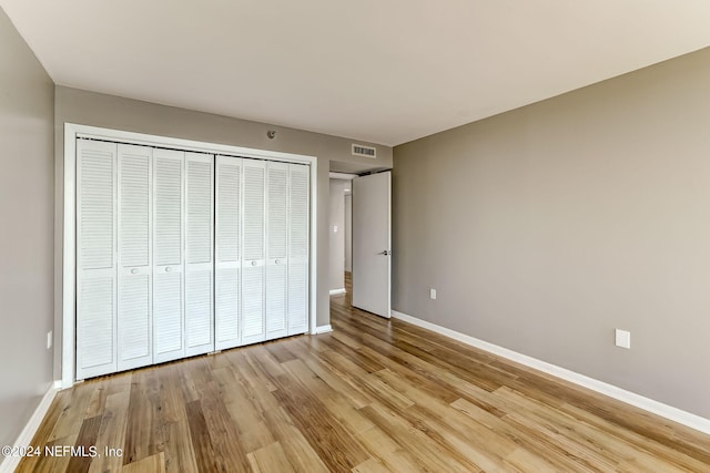 unfurnished bedroom with light wood-type flooring and a closet