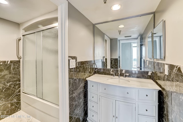 bathroom featuring vanity, enclosed tub / shower combo, and tile walls