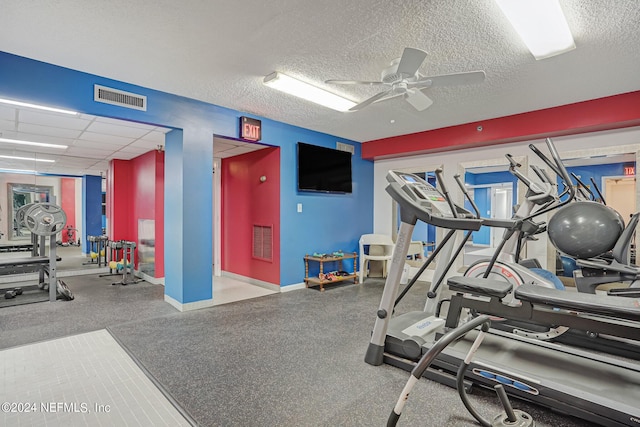 exercise room with a textured ceiling, ceiling fan, and a paneled ceiling