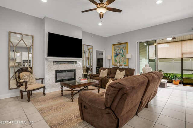 living room with light tile patterned floors, ceiling fan, and a stone fireplace