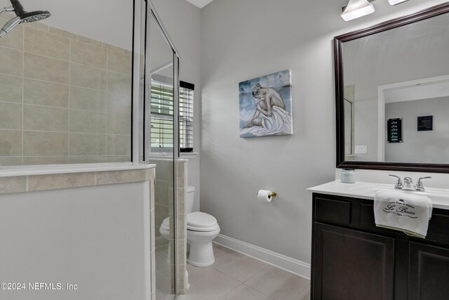 bathroom with tile patterned floors, toilet, a tile shower, and vanity