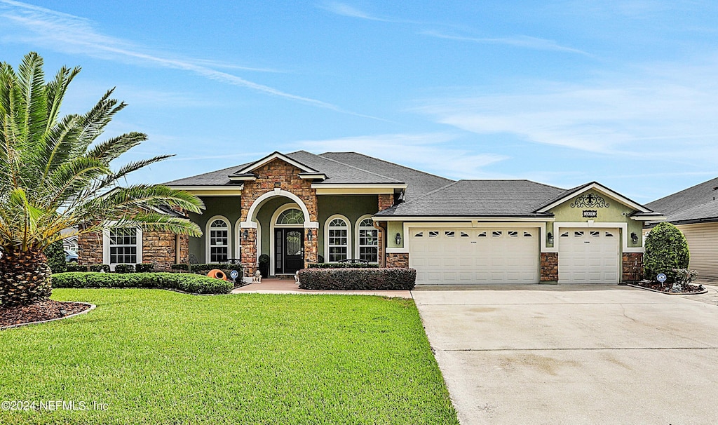 4506 Song Sparrow Dr, Middleburg, FL 32068 - view of front of property featuring stone siding, a front lawn, concrete driveway, and an attached garage