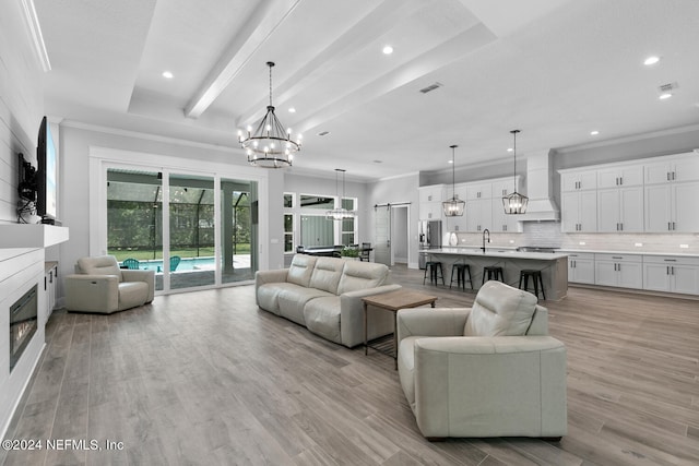 living room featuring beam ceiling, light hardwood / wood-style flooring, a raised ceiling, and sink