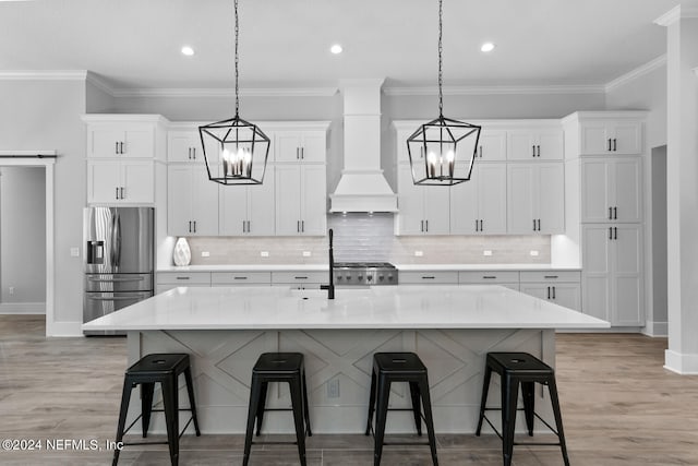 kitchen with a kitchen bar, a spacious island, stainless steel refrigerator with ice dispenser, and custom exhaust hood