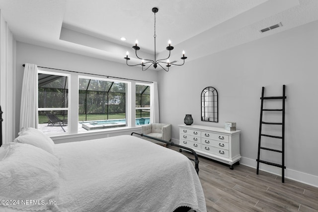 bedroom featuring dark hardwood / wood-style flooring, an inviting chandelier, and a raised ceiling