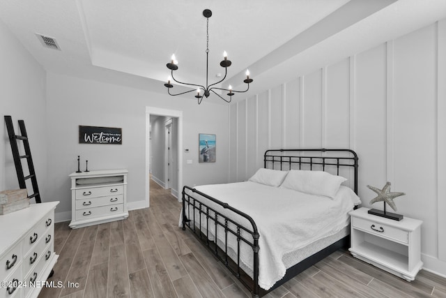 bedroom featuring a raised ceiling and an inviting chandelier