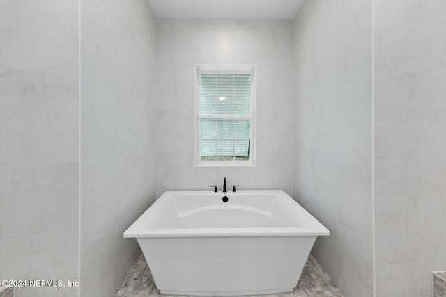 bathroom featuring a washtub and tile walls