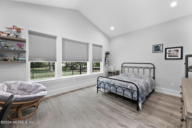 bedroom with light hardwood / wood-style floors and lofted ceiling