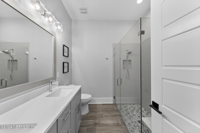 bathroom featuring vanity, toilet, and a shower with shower door