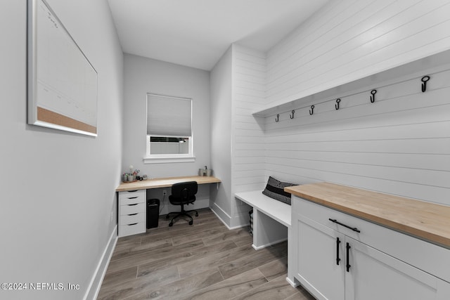 mudroom featuring built in desk, light hardwood / wood-style floors, and wooden walls