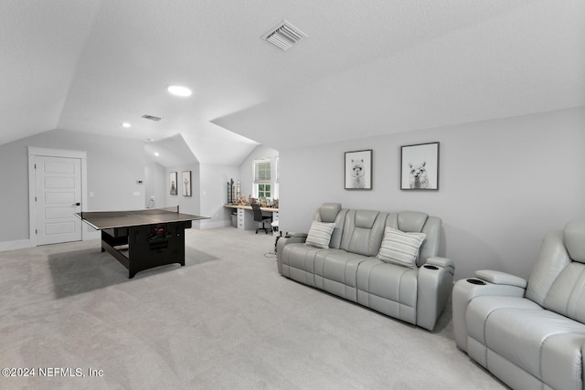 recreation room with a textured ceiling, light colored carpet, and vaulted ceiling