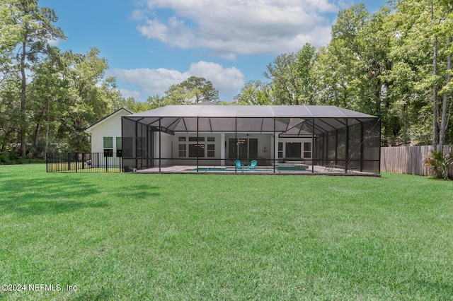 rear view of house with a lawn, glass enclosure, and a swimming pool