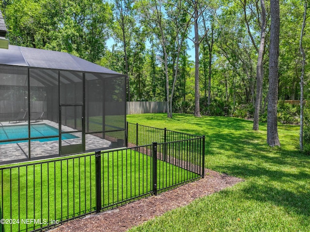 view of yard with a fenced in pool and glass enclosure