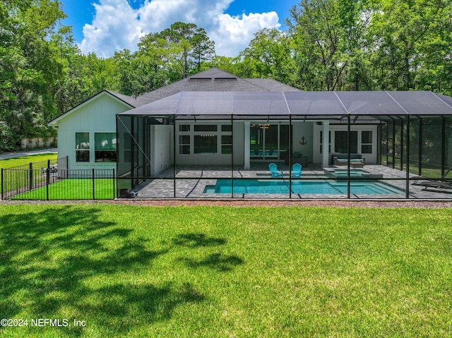 rear view of house with glass enclosure, a patio area, and a yard