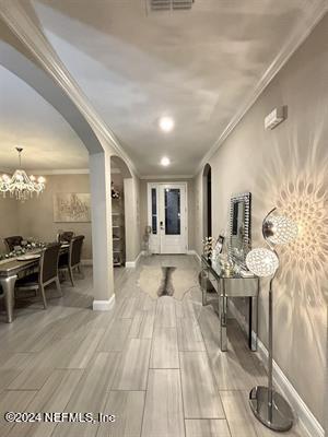 corridor with ornamental molding and a chandelier