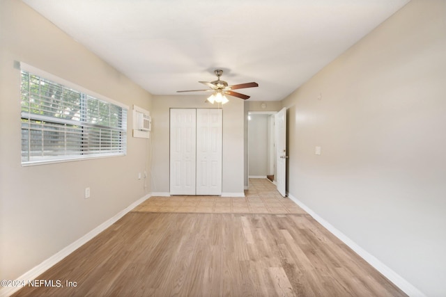 unfurnished bedroom featuring a wall mounted AC, ceiling fan, a closet, and light hardwood / wood-style floors