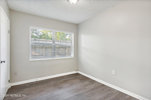 spare room with a textured ceiling and dark hardwood / wood-style floors