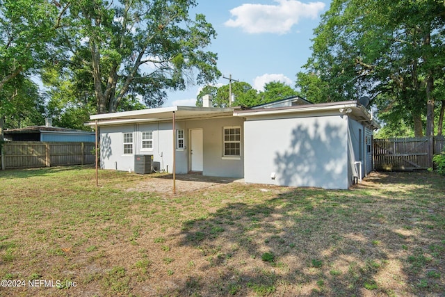 rear view of house with a yard and cooling unit