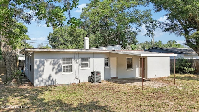 rear view of house featuring central AC and a lawn