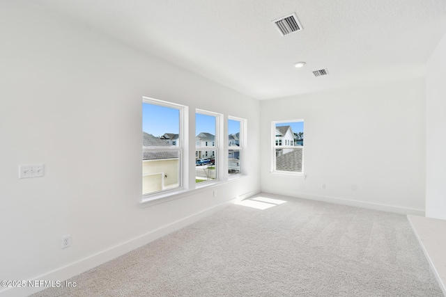 empty room with carpet flooring, visible vents, and baseboards