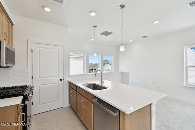 kitchen with decorative light fixtures, stainless steel appliances, visible vents, light countertops, and a sink