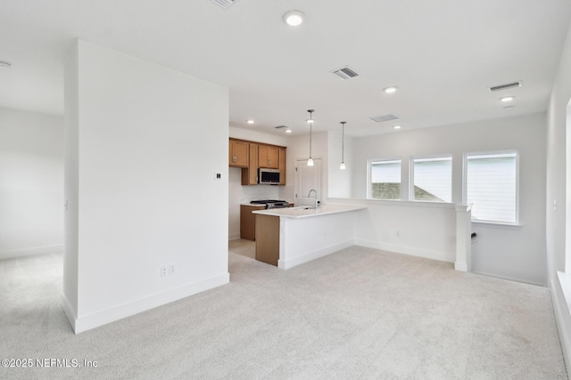 kitchen with brown cabinets, decorative light fixtures, light countertops, visible vents, and stainless steel microwave