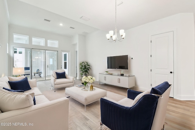 living room with light wood-style floors, visible vents, baseboards, and an inviting chandelier