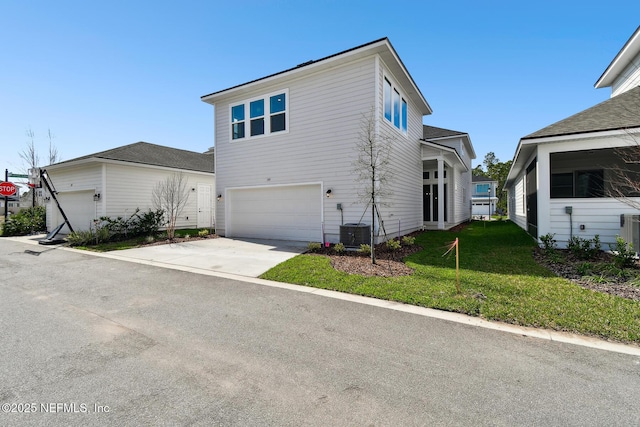 view of front of house featuring cooling unit, an attached garage, driveway, and a front lawn