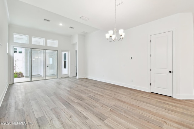 unfurnished room featuring light wood-style flooring, baseboards, and a notable chandelier