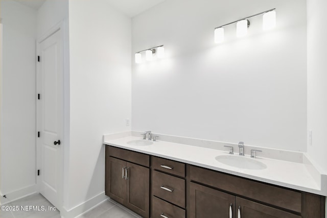 bathroom featuring a sink, baseboards, and double vanity