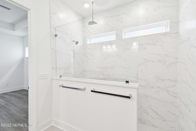 bathroom with baseboards, a marble finish shower, visible vents, and wood finished floors