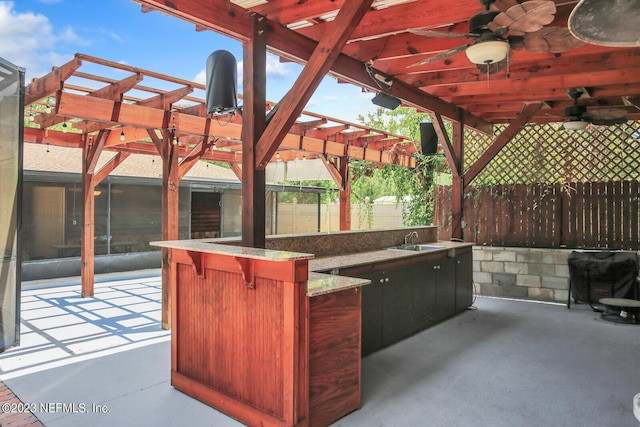 view of patio / terrace featuring ceiling fan, a sink, fence, outdoor dry bar, and a pergola