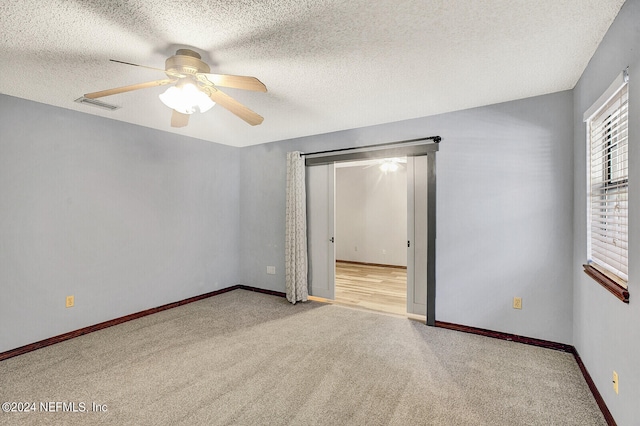unfurnished bedroom featuring visible vents, a ceiling fan, carpet flooring, a textured ceiling, and baseboards