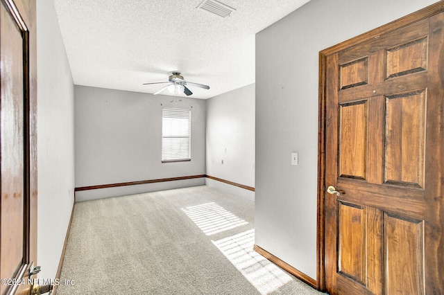 empty room with a ceiling fan, light colored carpet, visible vents, and a textured ceiling