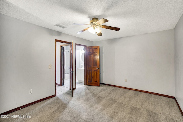 empty room featuring a ceiling fan, light carpet, visible vents, and baseboards
