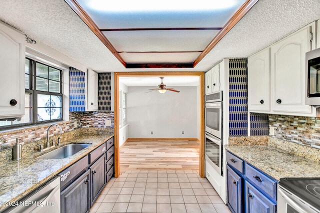 kitchen with light tile patterned floors, decorative backsplash, appliances with stainless steel finishes, white cabinetry, and a sink