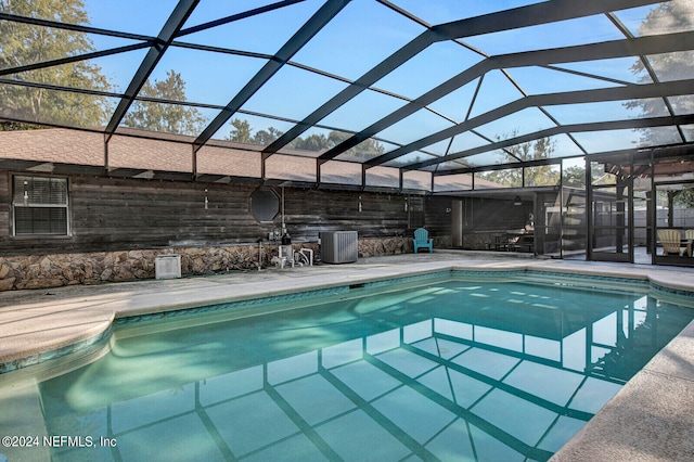 outdoor pool featuring glass enclosure and a patio area