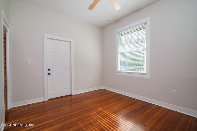 unfurnished room featuring ceiling fan, baseboards, and dark wood-type flooring