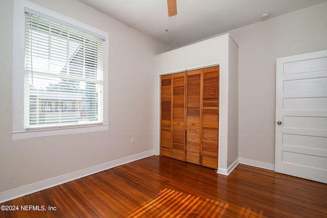 unfurnished bedroom featuring ceiling fan, a closet, wood finished floors, and baseboards