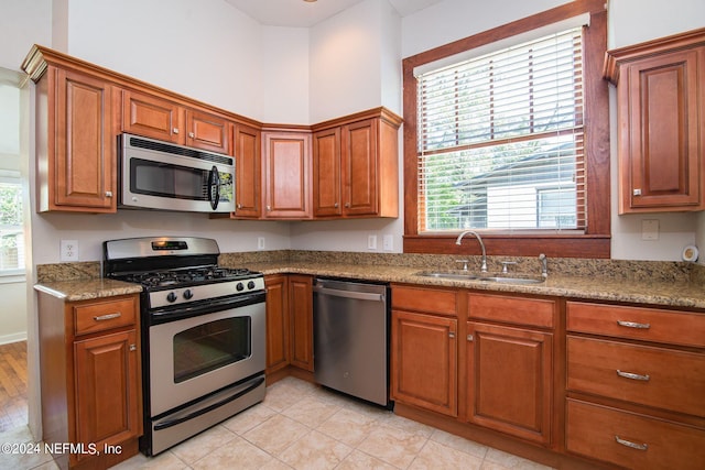 kitchen featuring a wealth of natural light, appliances with stainless steel finishes, brown cabinetry, and a sink