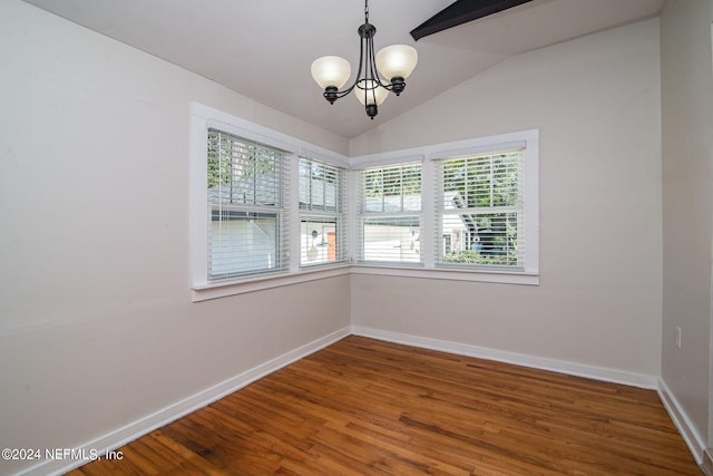 spare room with lofted ceiling, an inviting chandelier, baseboards, and wood finished floors